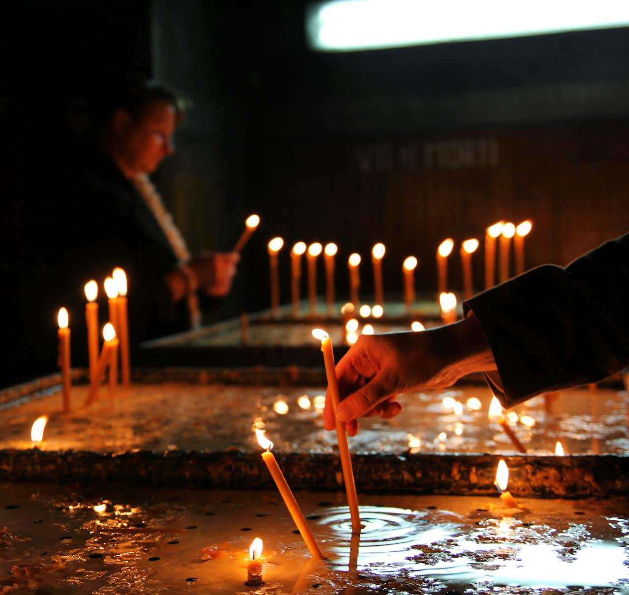 A solemn candle lighting ceremony in a dimly lit church setting symbolizing faith and prayer.